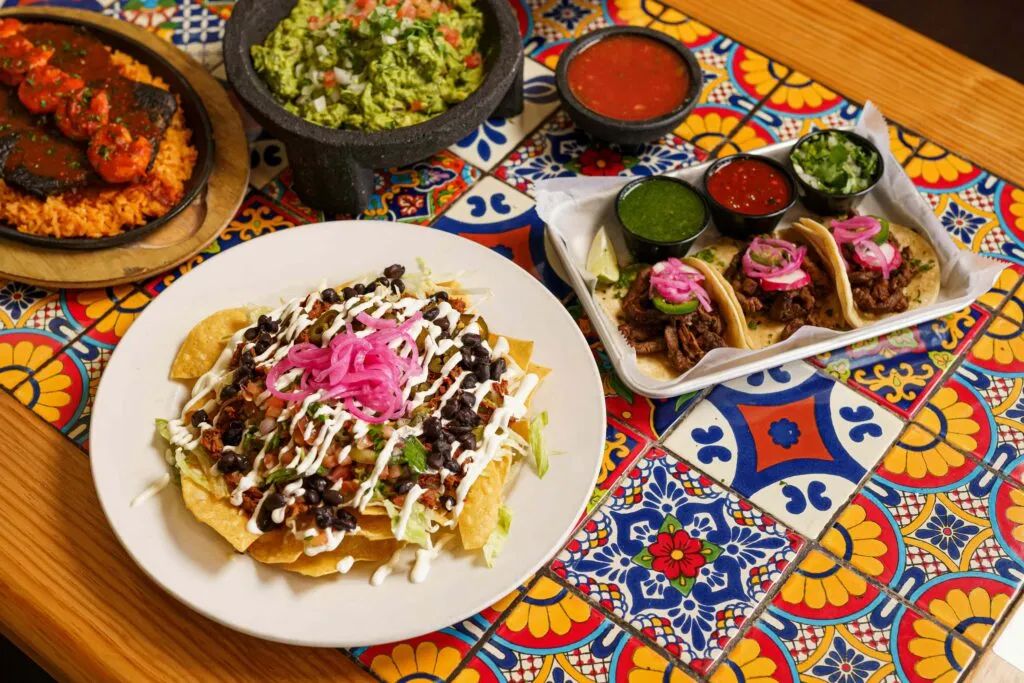 Mesa mexicana con pozole, tostadas horneadas, verduras frescas y agua de jamaica sin azúcar.
