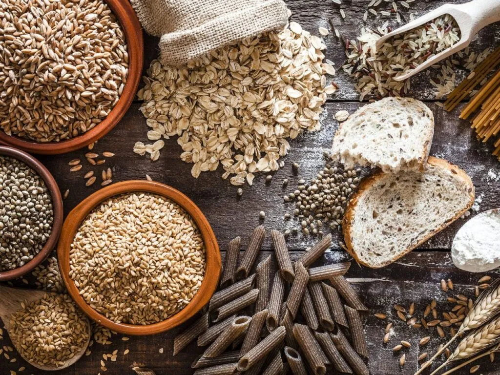 Alimentos integrales como avena, cereales, legumbres y frutos secos para una alimentación saludable