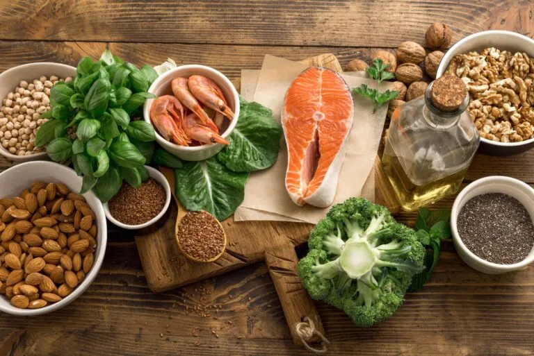 Alimentos para prevenir la migraña con verduras frescas, pescado azul, frutas y aceite de oliva