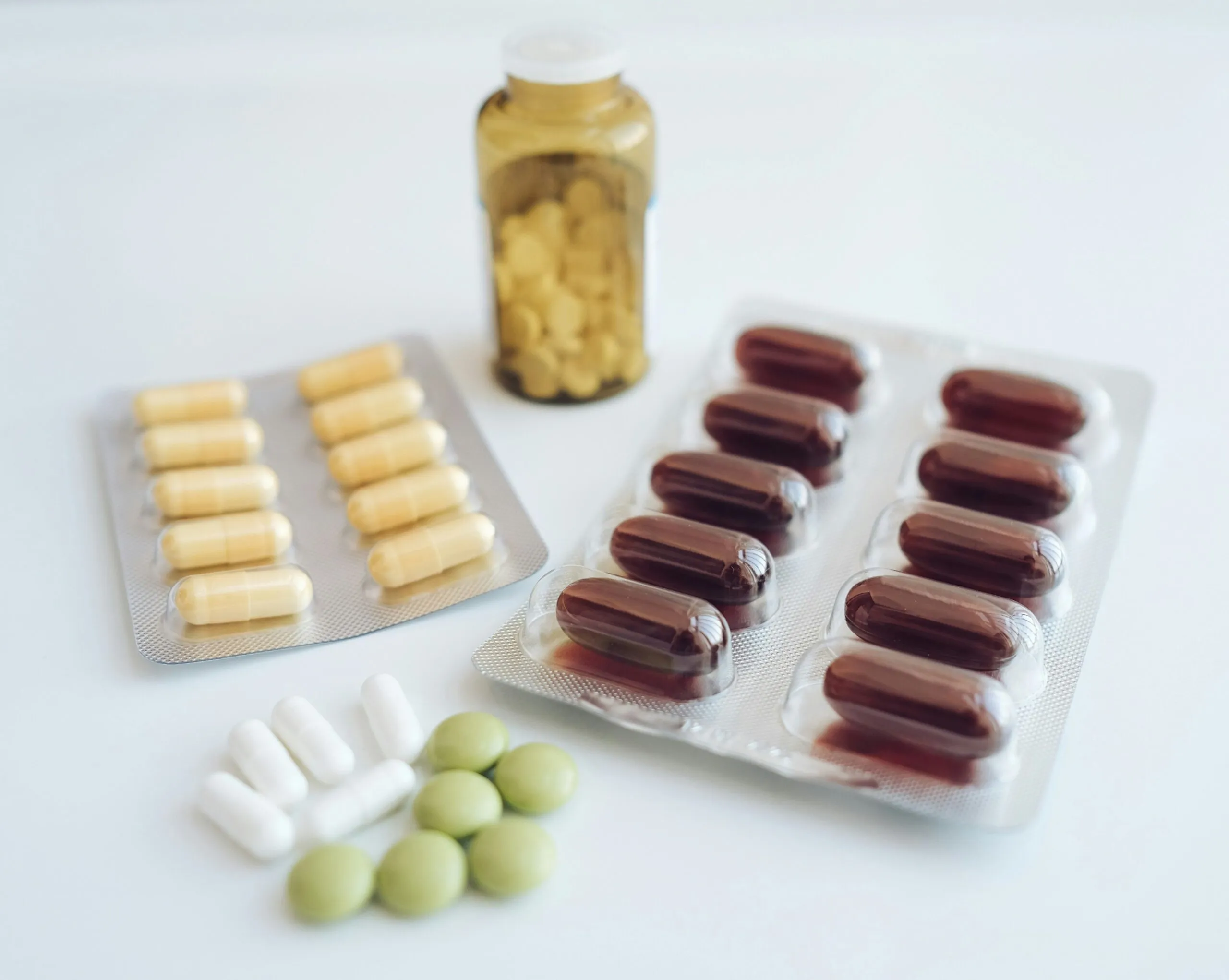 Suplementos alimenticios junto a frutas, verduras y legumbres que representan una dieta variada y hábitos saludables.