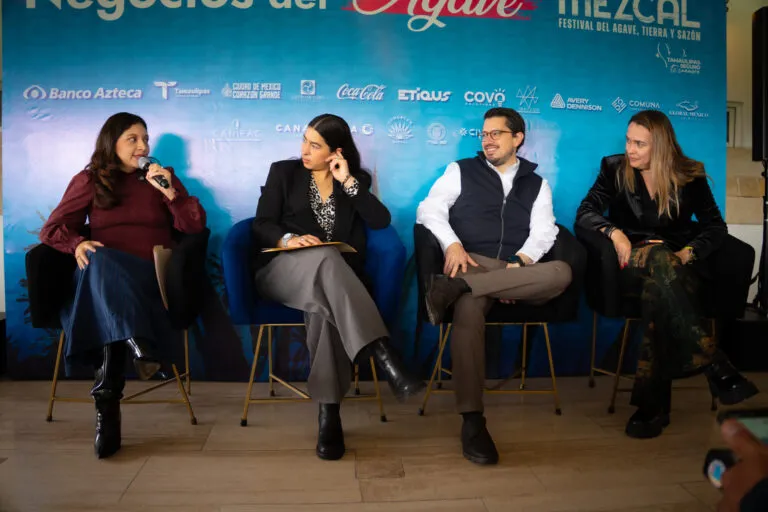 Cuatro participantes conversan durante un panel de Negocios del Agave en Mundo Mezcal, frente a un fondo con el logotipo de Banco Azteca.